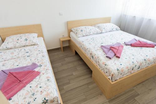 two beds in a small room with two towels at Apartments Villa Monique in Rogoznica