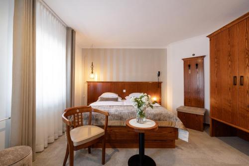 a bedroom with a bed and a table and a chair at Hotel Kotnik in Kranjska Gora