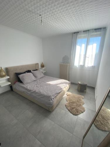 a white bedroom with a bed and two windows at Location T3 entier à 5 minutes de l’aéroport in Marignane