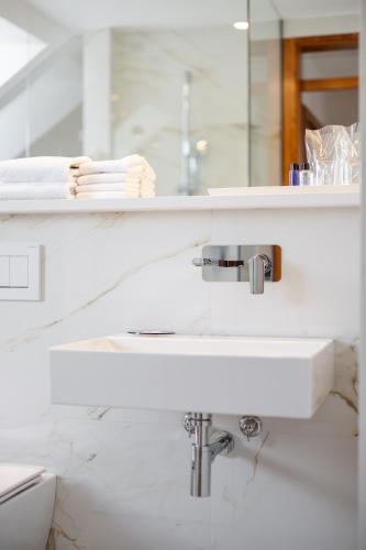 a white bathroom with a sink and a mirror at Kotnik Superior Boutique Hotel in Kranjska Gora