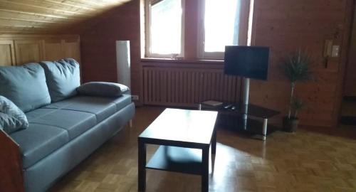 ein Wohnzimmer mit einem Sofa und einem Tisch in der Unterkunft 2-Zimmer DG-Apartment mit eigener Sauna in Oberhaching