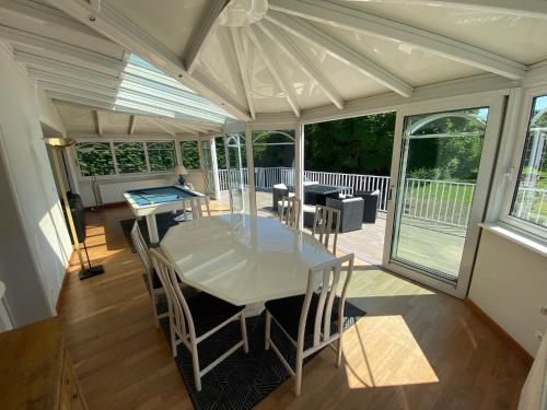 une véranda avec une table blanche et des chaises sur une terrasse dans l'établissement Magnifique villa à 5 minutes de Colmar, à Horbourg-Wihr