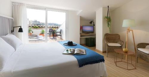 a bedroom with a large white bed and a living room at Augusta Club & Spa - Adults Only in Lloret de Mar