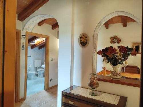 un baño con espejo y un jarrón de flores sobre una mesa en Cottage "Le None"-villa e giardino, en Gonàrs