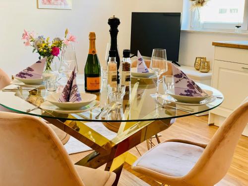 een glazen eettafel met wijnflessen en stoelen bij Ferien-Apartment Silberweide mit Privatstrand in Friedrichshafen