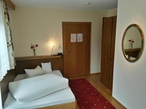 a bedroom with a white bed and a mirror at Gasthof Pension Traube in Karres