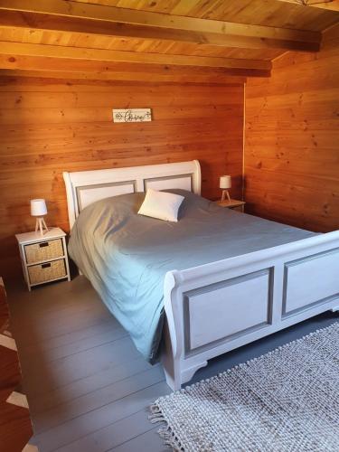 a bedroom with a white bed in a wooden room at DOMAINE DES GALLINACES CHALET SUSSEX 2-4p in Marigny-lès-Reullée