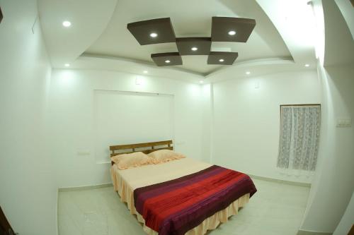 ThodupuzhaにあるThodupuzha 4-bhk Luxury Home awy from homeの白いベッドルーム(ベッド1台、天井付)