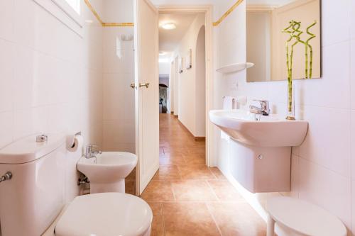 a white bathroom with a toilet and a sink at Villa SUN PARADISE in Son Bou