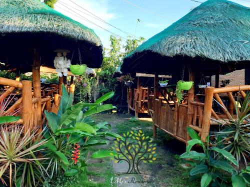 a restaurant with a straw umbrella and some plants at MJ's Residences Garden Hotel in Moalboal