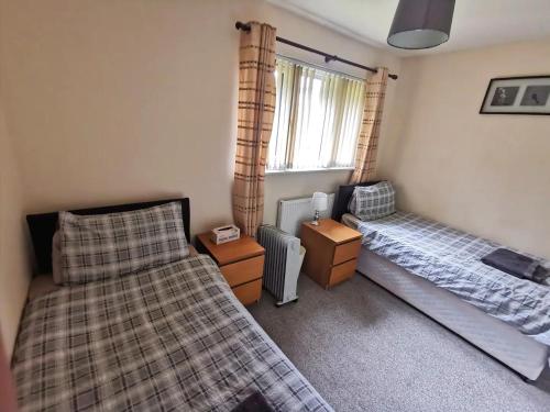 een slaapkamer met 2 bedden en een raam bij Glasgow's Cosy Family Home Near SECC Hydro in Glasgow