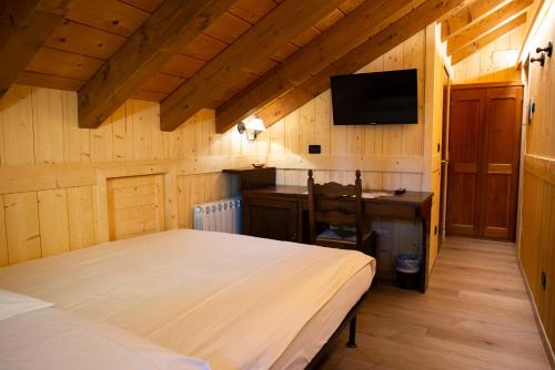 a bedroom with a bed and a desk and a television at Santa San in Champoluc