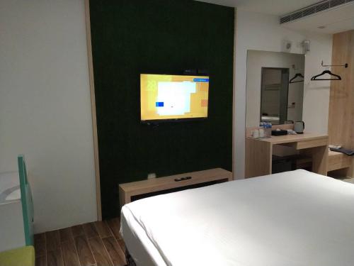a bedroom with a bed and a tv on a wall at π 園周綠溫泉會館-泉鄉雅舍 in Jiaoxi