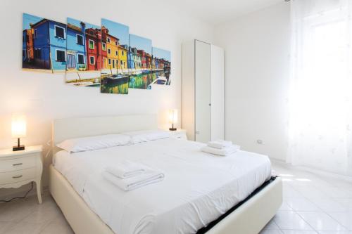 Un dormitorio con una cama blanca y una pintura en la pared en 15 - Tourist House Bologna Primaticcio - Self check-in, en Bolonia