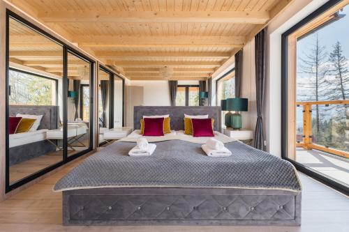 a large bed in a room with large windows at Osada Gubałówka na Polanie Pająkówka & SPA in Kościelisko