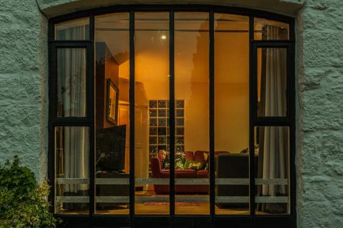 een raam van een woonkamer met een persoon op een bank bij No.1 The Coach House in Silverdale