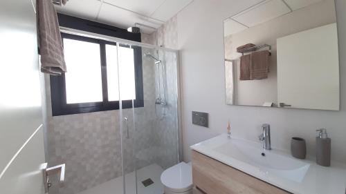 uma casa de banho com um chuveiro, um lavatório e um WC. em Villa Wilhelmina em Torrevieja