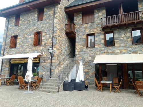 a building with chairs and umbrellas in front of it at La Coma in Taull