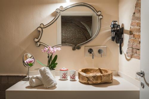 a bathroom sink with a mirror and flowers on it at Domu Manca in Torpè