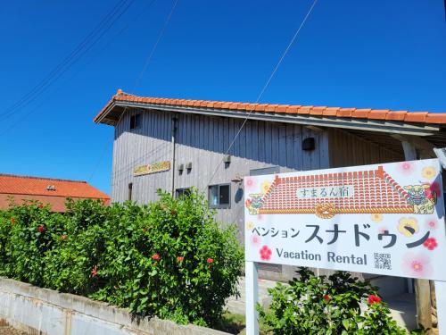 a sign in front of a building with aoren yard at Pension Snadun in Ginoza