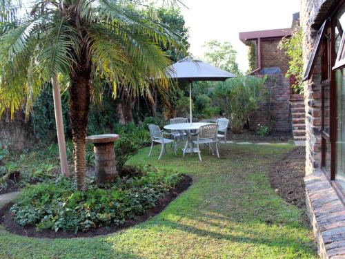 a table and chairs with a palm tree and an umbrella at Cosy-Corner Guest House, George in George