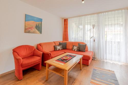 a living room with an orange couch and a table at Ferienhaus Grünten in Fischen