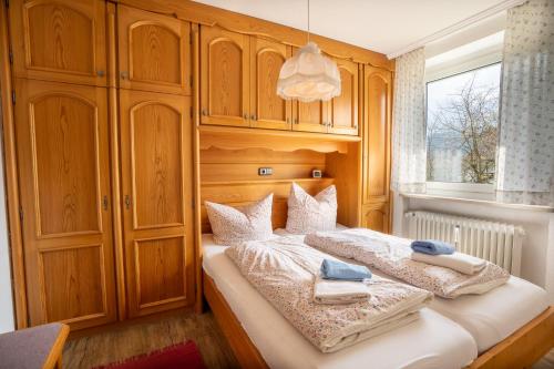 1 dormitorio con 2 camas, armarios de madera y ventana en Ferienhaus Grünten, en Fischen
