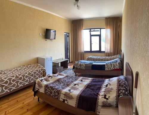 a hotel room with two beds and a television at Guest House Janel in Cholpon-Ata
