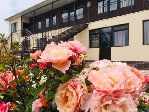 un montón de rosas rosas delante de un edificio en Guest House Janel, en Cholpon-Ata