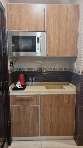 a kitchen with wooden cabinets and a microwave at فندق السد الخليجى in Sīdī Ḩamzah