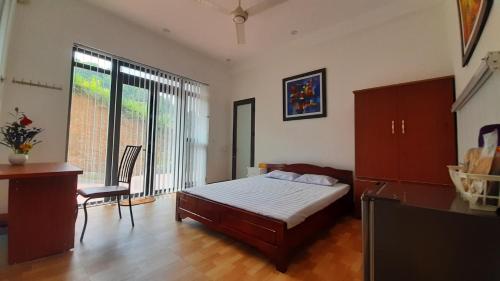 a bedroom with a bed and a desk and a window at Mountain Breath Retreat - Am Nui Tho in Yen Bai
