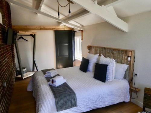 1 dormitorio con 1 cama blanca grande con almohadas azules en Chambres d'Hôtes et Gîte de La Vieille Ecluse en Quend
