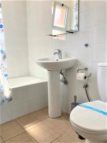 a white bathroom with a sink and a toilet at Ariadne Apartments in Paphos City