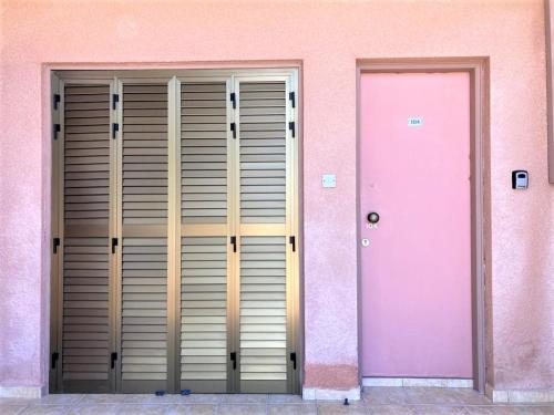 a pink building with two doors and a pink wall at Ariadne Apartments in Paphos City