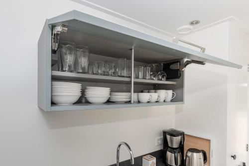 a kitchen with a shelf with dishes in it at Vakantiehuis '2bijZee' dicht bij Domburg en strand in Aagtekerke