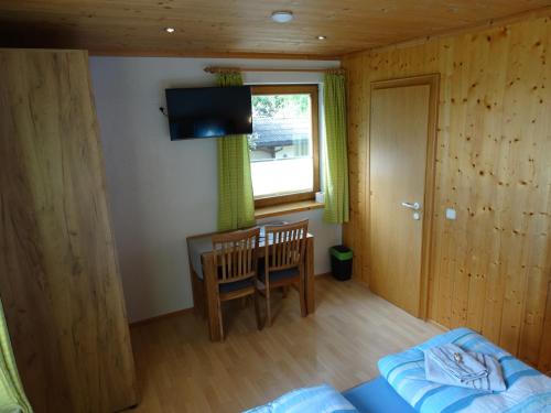 a bedroom with a bed and a table and a window at Gästehaus Posch in Krimml