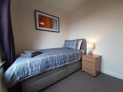 a small bedroom with a bed and a night stand at Carvetii - Xavier House - 2-storey sleeps up to 7 in Rosyth