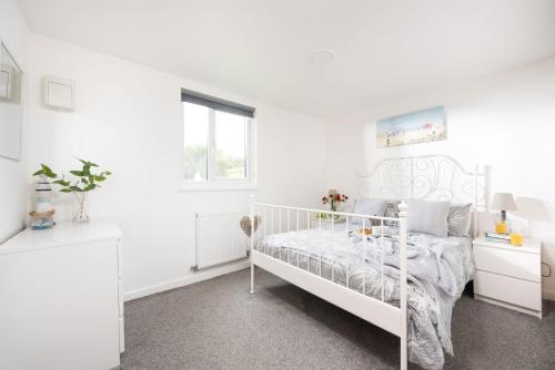 a white bedroom with a white bed and a window at Wheal Jewel- Beautifully Fitted Wooden Lodge Helston Cornwall in Helston