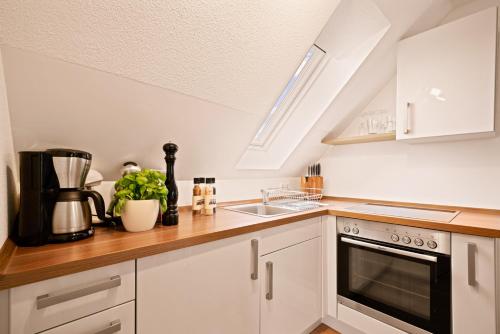 a kitchen with white cabinets and a sink at Ferien-Apartment Haubentaucher - mit priv Strandzugang in Friedrichshafen