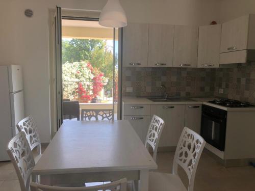 een keuken met een witte tafel en stoelen en een keuken met een raam bij Calanovella Mare piano terra 5 in Piraino