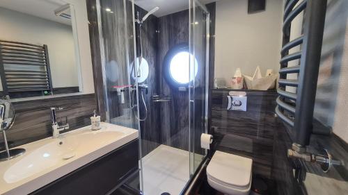 La salle de bains est pourvue d'une douche, d'un lavabo et de toilettes. dans l'établissement Hausboot La Mare Gabi, à Weyhe
