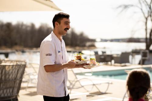 a man holding a plate of food next to a pool at Gränsö Slott Hotel & Spa in Västervik