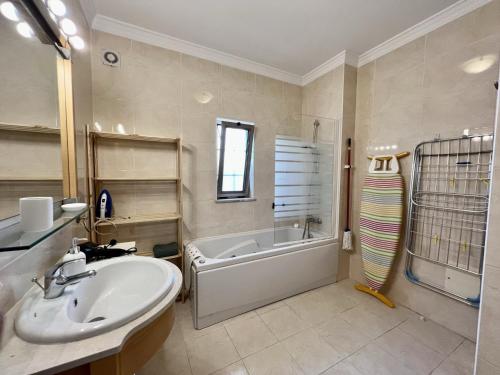 Un baño con bañera, lavabo y bañera. en Albufeira Terrace With Pool by Homing, en Albufeira
