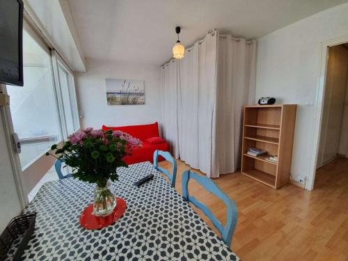 une pièce avec une table avec un vase de fleurs dessus dans l'établissement Studio cosy à 50m de la plage - 4 couchages, loggia vue mer, lave-linge, ménage inclus - FR-1-224C-418, à Saint-Hilaire-de-Riez
