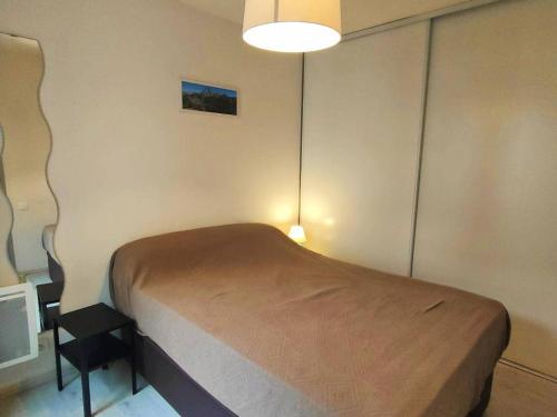 Un dormitorio con una cama con una lámpara y una silla. en Appartement lumineux 4-6 pers, parking à Cauterets - FR-1-234-199, en Cauterets
