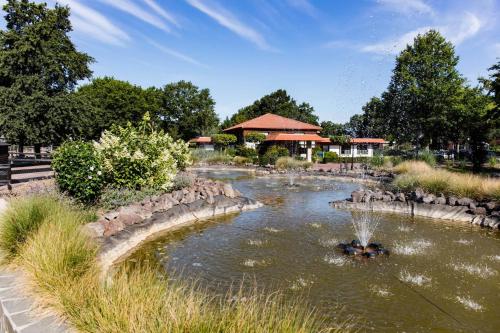 a pond in a park with a fountain at EuroParcs Limburg in Susteren