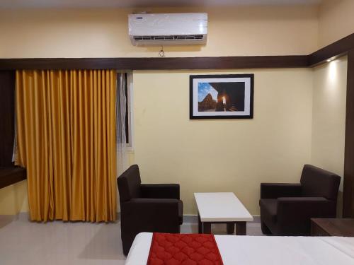 a hospital room with a bed and two chairs and a table at sri balaji grand hotel in Kumbakonam