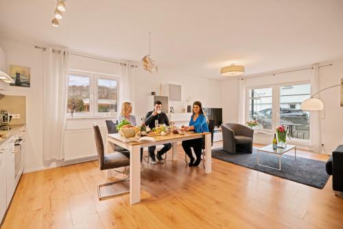 a group of people sitting at a table in a kitchen at Ferien-Apartment Auenwald - mit priv Strandzugang in Friedrichshafen