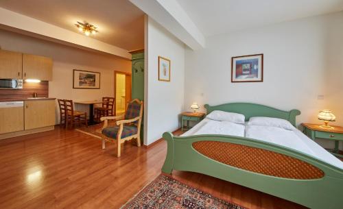 a bedroom with a green bed and a kitchen at Chalet Haider in Saalbach Hinterglemm