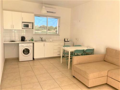 a living room with a couch and a table and a kitchen at Ariadne Apartments in Paphos City